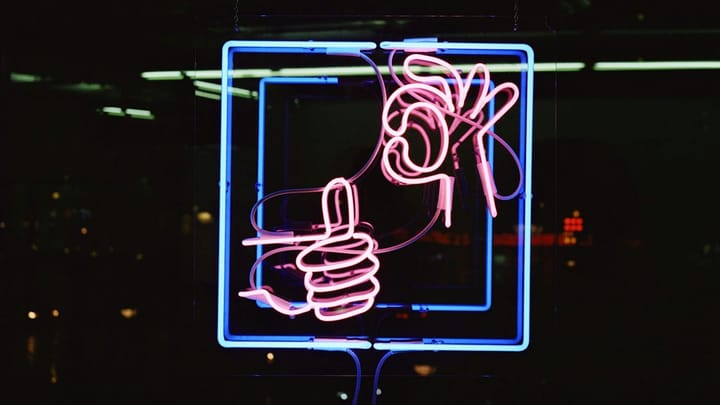 A neon sign showing a thumbs up and "OK" hand signal.